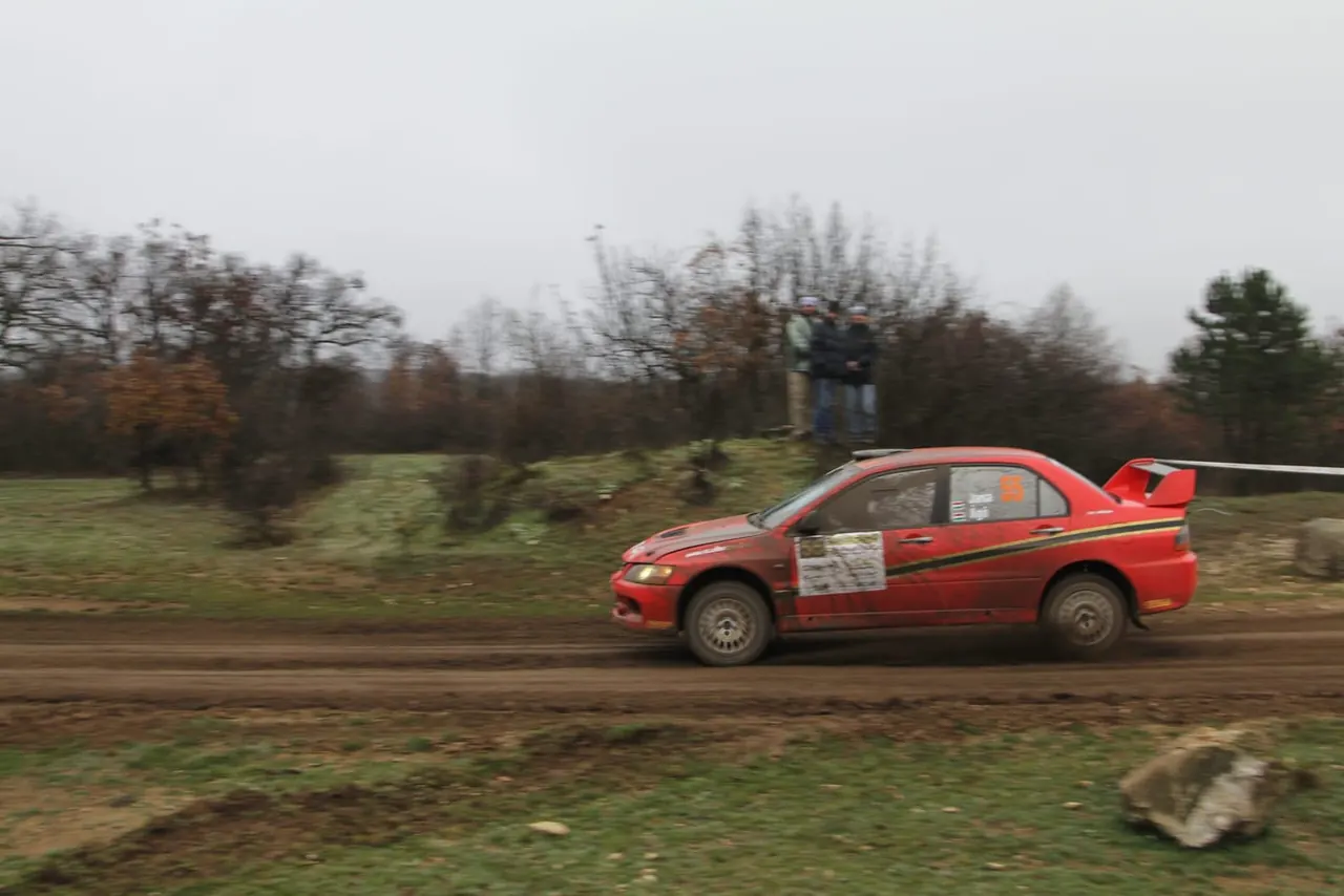 A red rally car on a stage of the Mikulás Rallye